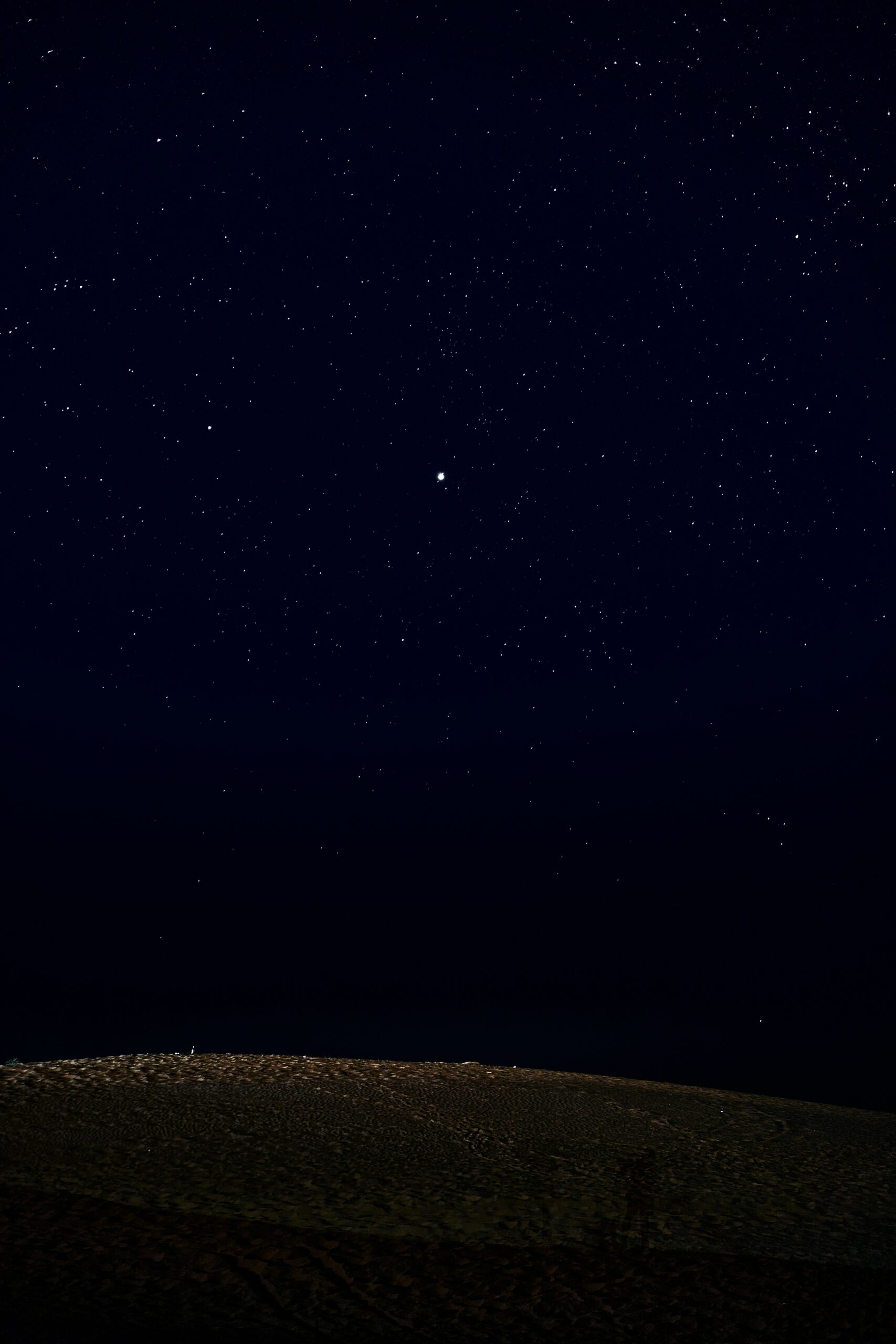 A man standing on top of a hill under a night sky filled with stars